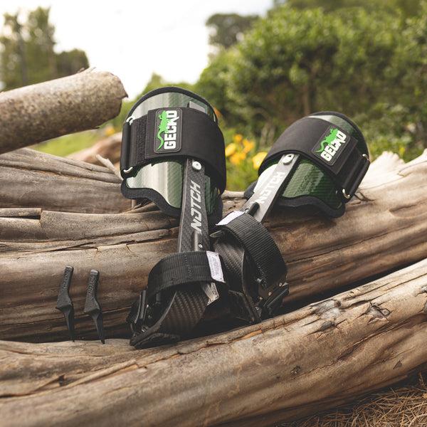 Gecko Carbon Fiber 2.0 climbers resting on a log with spare pole gaffs